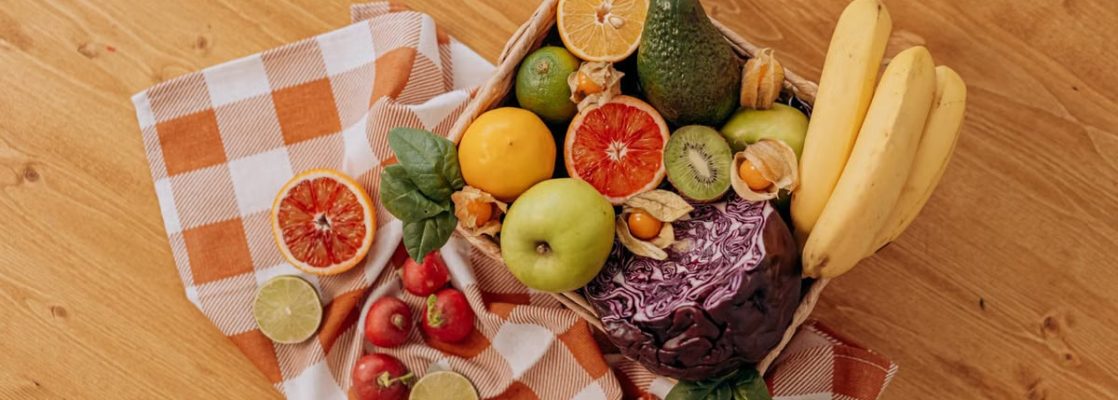 A vibrant flat lay of assorted fresh fruits on a checkered cloth over a wooden surface, perfect for healthy lifestyle concepts.