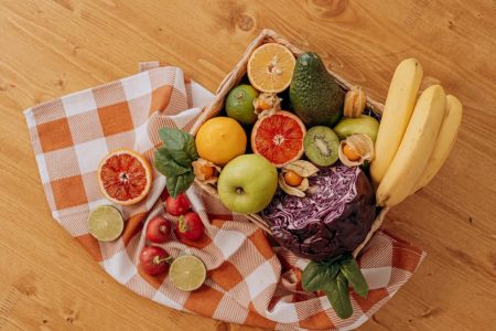 A vibrant flat lay of assorted fresh fruits on a checkered cloth over a wooden surface, perfect for healthy lifestyle concepts.