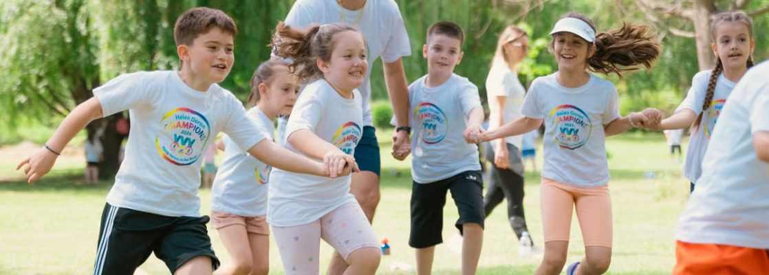 Children joyfully running and holding hands in a sunny park, enjoying outdoor recreation.