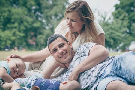 Happy family enjoying a sunny day outdoors, with parents and children lying on the grass.