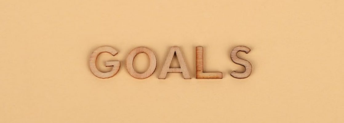 Wooden letters spelling 'GOALS' on a plain background, emphasizing motivation.