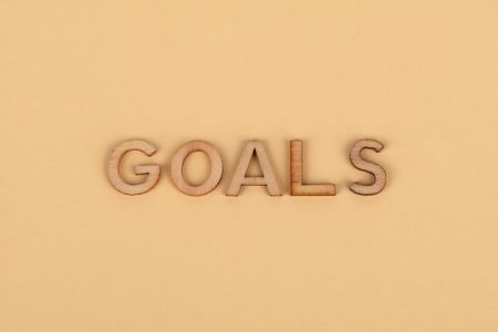 Wooden letters spelling 'GOALS' on a plain background, emphasizing motivation.
